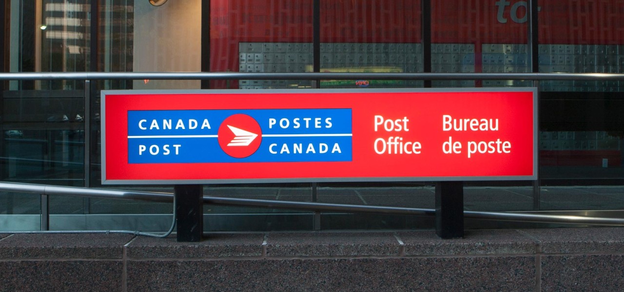 Close up of a large post office sign featuring the bilingual Canada Post logo