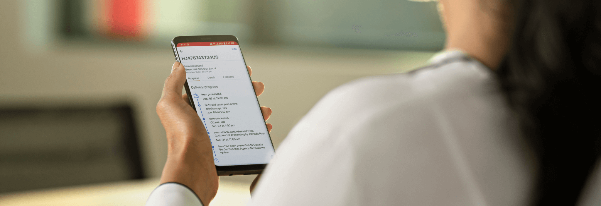 A woman uses the Canada Post app at home on her smartphone. 