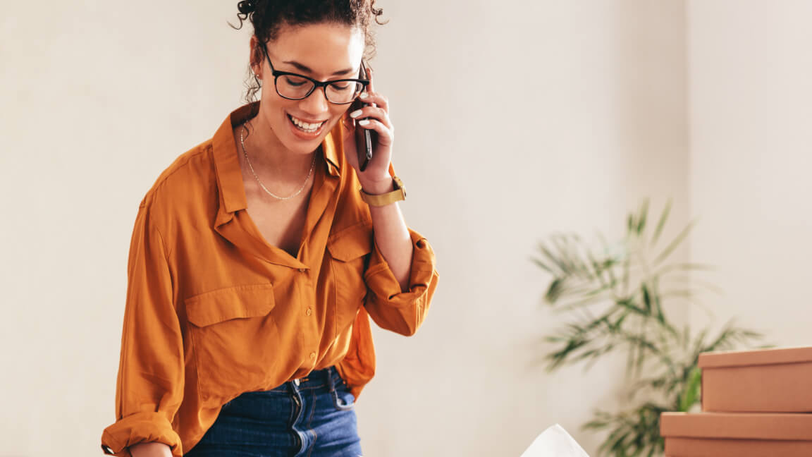 A woman smiles as she talks on the phone.