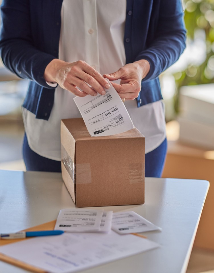 A woman affixes a Canada Post return label to the top of a package.