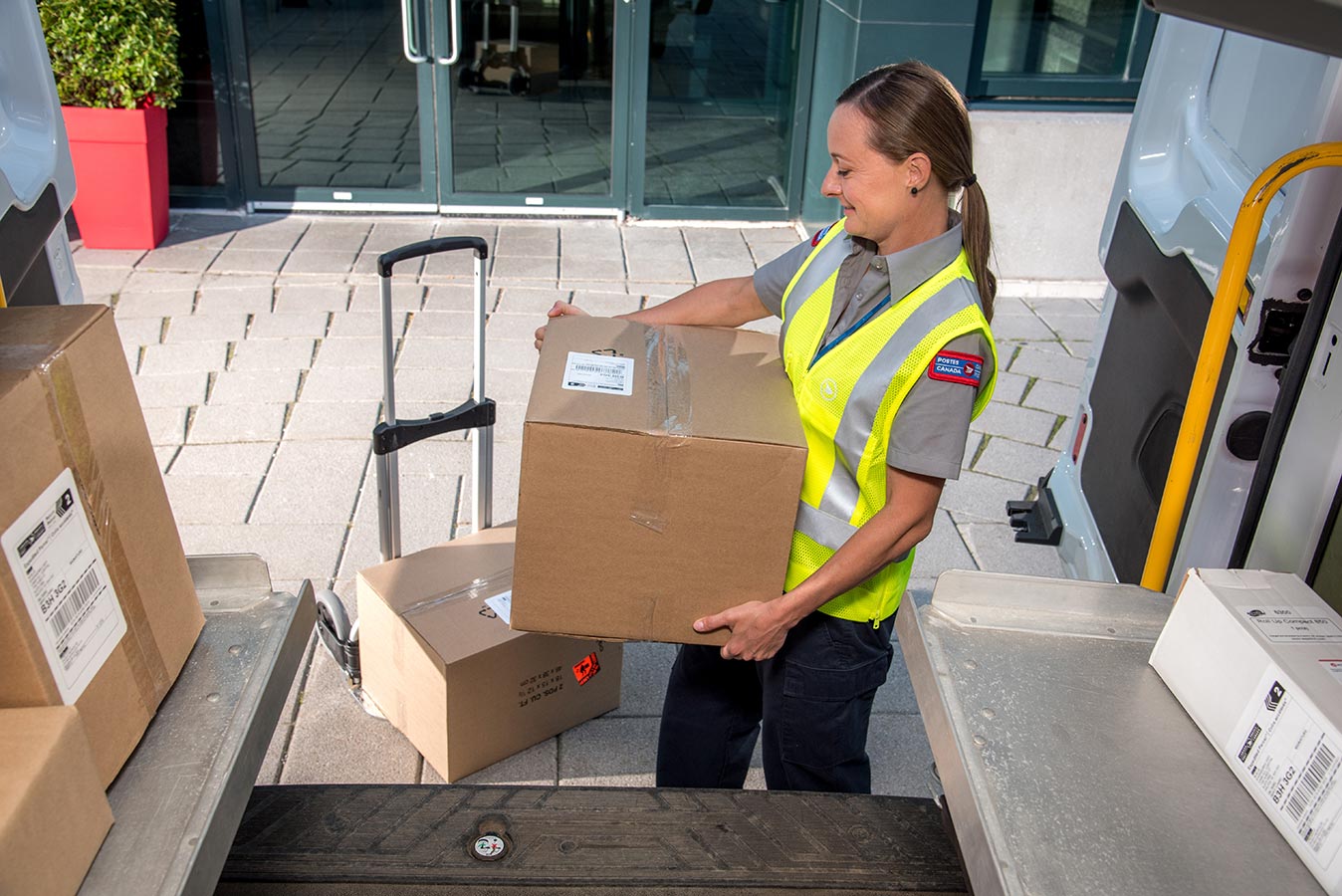 Delivery agent transferring packages from a mail truck to a dolly