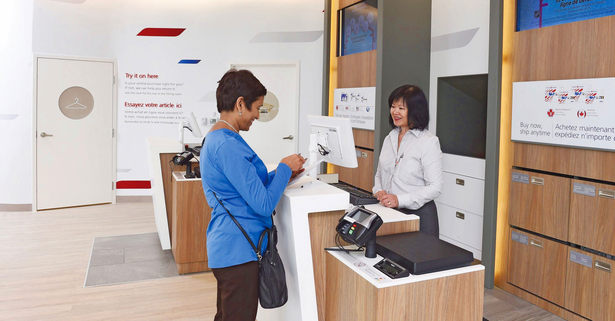 A woman smiles at a clerk and removes something from her wallet at a post office.